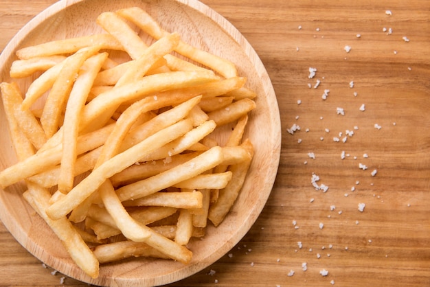 Batatas fritas no fundo de madeira.