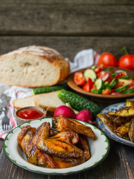 Batatas fritas, salada, legumes em um fundo de madeira velho. Jantar rural, piquenique de verão. Fechar-se.