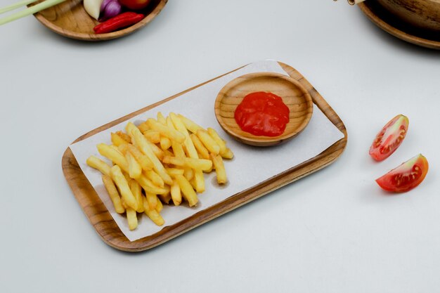 Batatas fritas servidas em uma placa de madeira com molho de tomate