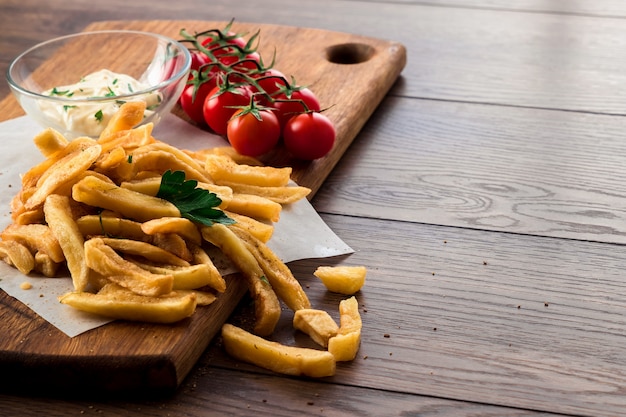 Batatas fritas, tomate cereja, molho de alho na madeira