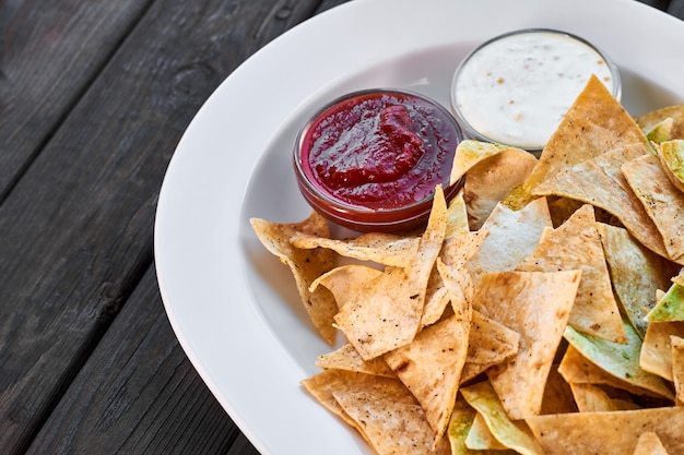 Batatas fritas triangulares de nachos com ketchup de tomate e molho de queijo em um prato