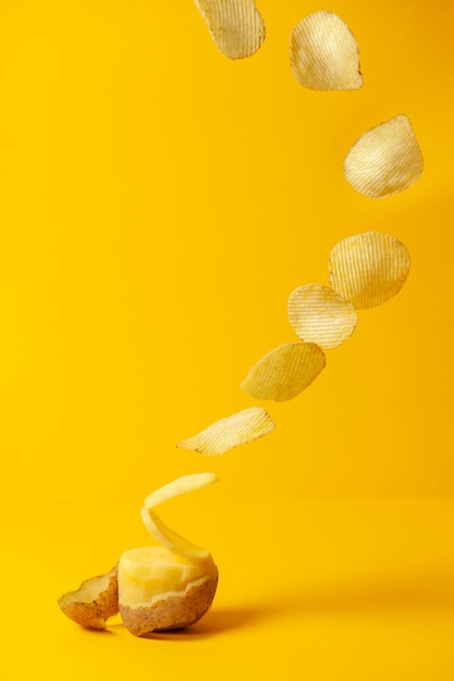 Foto batatas fritas voam sobre um fundo amarelo, o processo de fabricação de batatas fritas, levitação de fast-food