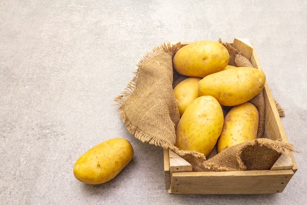 Batatas jovens com casca cru em uma caixa de madeira