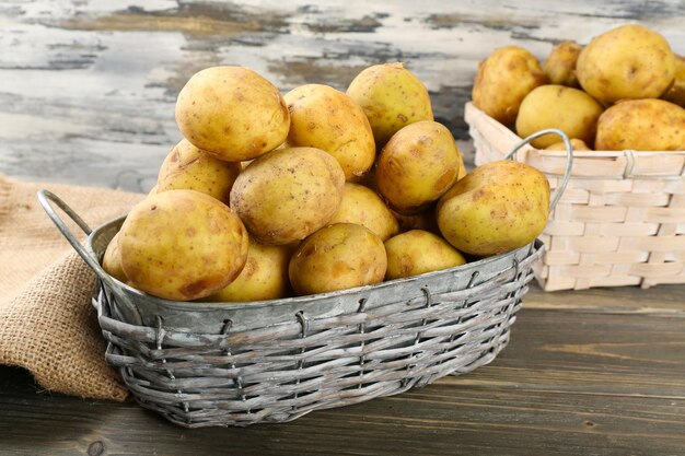 Batatas jovens em cestas de vime na mesa de madeira fecham