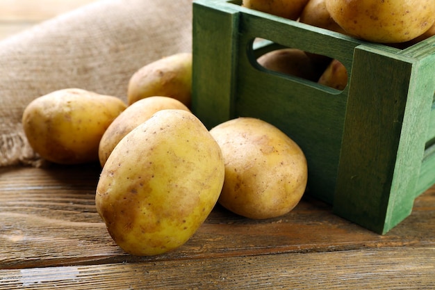 Batatas jovens na caixa na mesa fecham