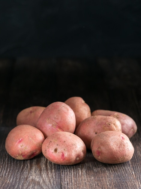 Batatas orgânicas inteiras cruas em fundo de madeira velho