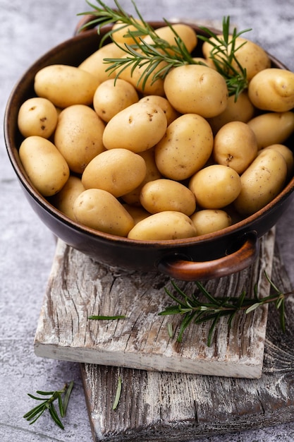 Batatas pequenas cruas em uma frigideira de ferro fundido em um fundo beton.