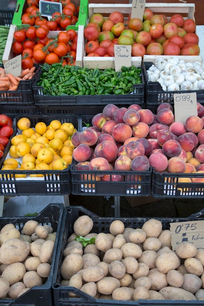 Batatas, pêssegos, pimentas, cogumelos e tomates na banca do mercado