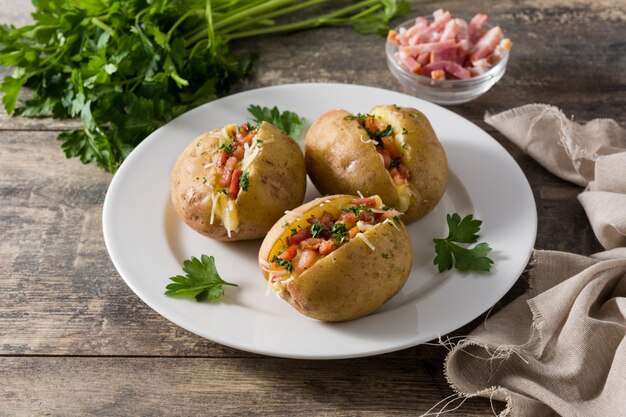 Batatas recheadas com bacon e queijo no prato na mesa de madeira