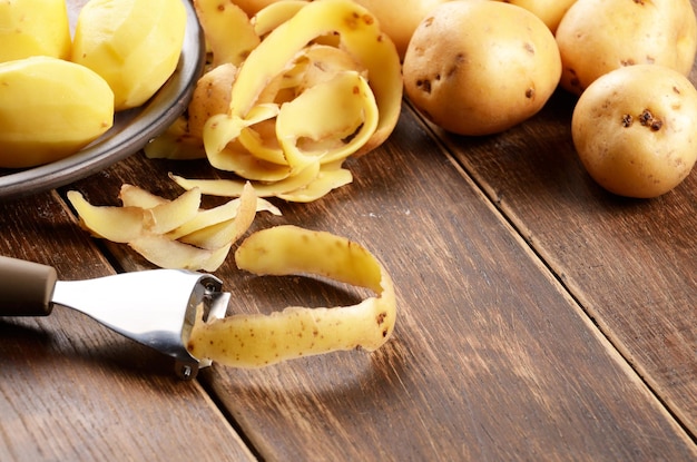 Batatas sendo descascadas na mesa de madeira