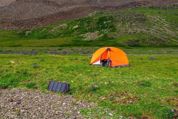 Bateria solar no acampamento. Caminhadas a solo nas pitorescas montanhas de verão. Acampar em um planalto de alta altitude rochoso verde de verão.