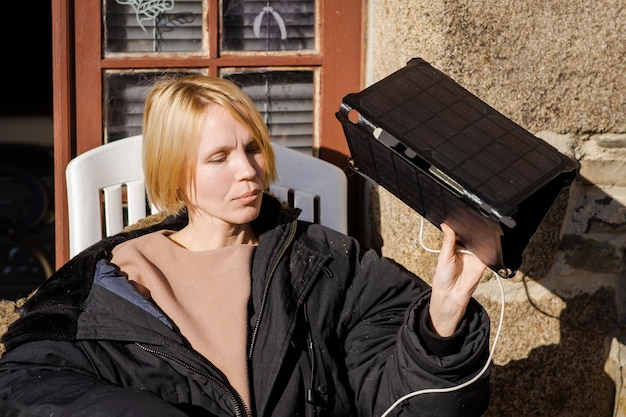 Batería solar portátil en manos de una mujer Cargando dispositivos móviles en la naturaleza sin electricidad Concepto de fuente de energía alternativa