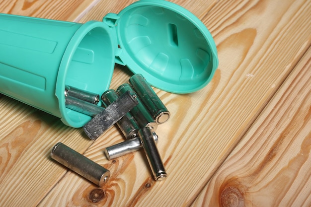 Baterías de dedos usadas en un contenedor de basura en miniatura en tablas de pino de cerca