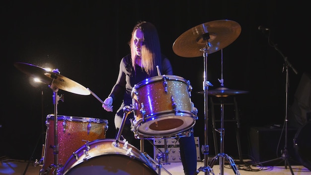 Baterista emocional, jovem e atraente modelo de cabelo preto tocando bateria, grande angular