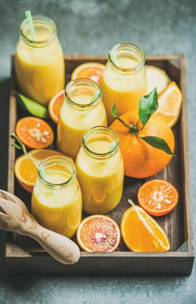 Batido amarillo saludable en botellas en bandeja de madera