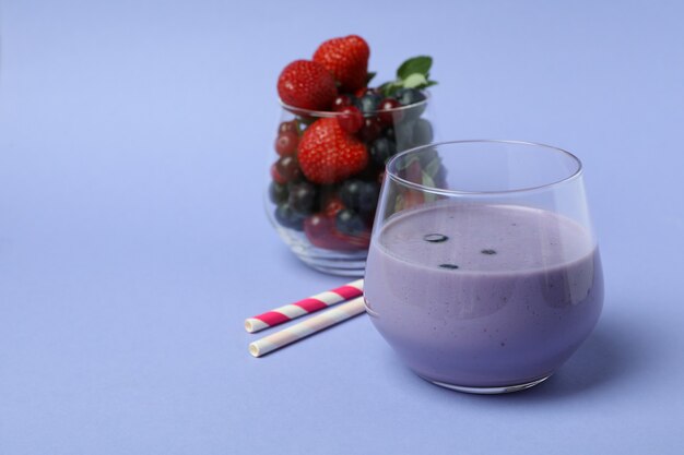 Batido de arándanos, ingredientes y pajitas sobre fondo violeta