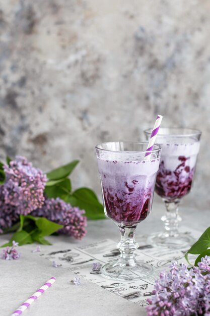 Foto batido de arándanos sobre fondo gris con flores lilas alimentación saludable vegana