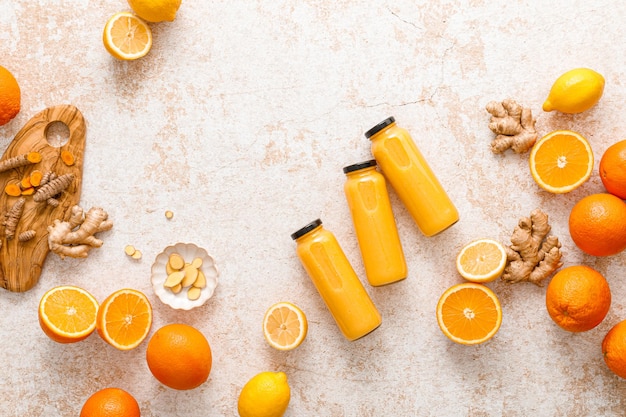 Batido Batido de cítricos de desintoxicación cruda fresca y saludable con naranja, limón, jengibre y cúrcuma en botellas de vidrio sobre una mesa Dieta saludable Comida vegana llena de antioxidantes