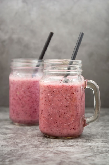 Batido de bayas en frasco de vidrio con hojas de menta, gris