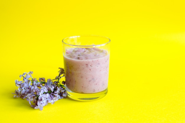 Batido de bayas frescas en un amarillo. Una rama de batido de lilas y bayas