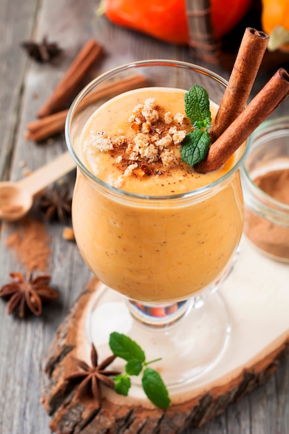 Batido de calabaza con canela y granola sobre la superficie de madera vieja. Enfoque selectivo.