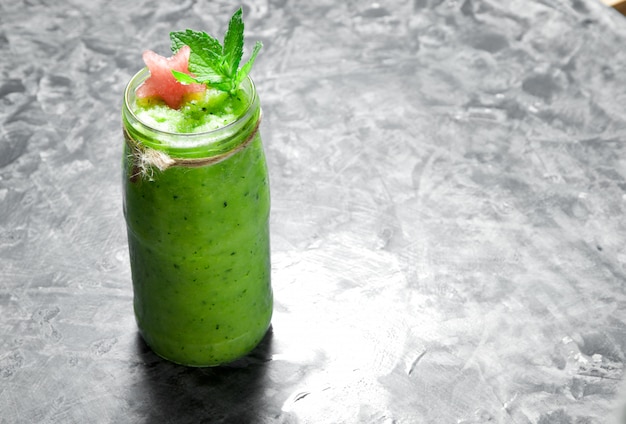 Batido de cóctel tropical con menta, rodajas de sandía y cubitos de hielo sobre una superficie de hormigón gris