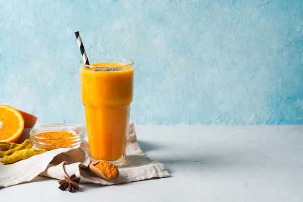 Batido de cúrcuma en vaso con ingredientes cúrcuma en polvo jengibre y especias en azul