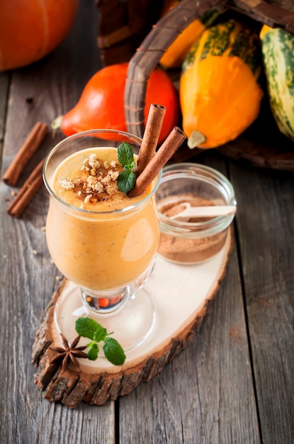 Batido de abóbora com canela e granola na superfície de madeira velha. Foco seletivo.