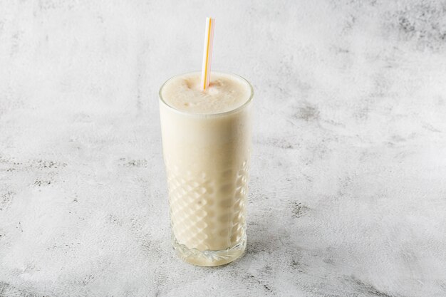 Batido de aveia de banana ou batido de baunilha em vidro no fundo de mármore brilhante. visão aérea, copie o espaço. publicidade para o menu de café milkshake. foto horizontal.