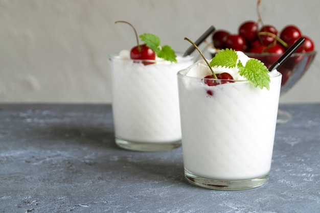 Batido de leite com cerejas. em um fundo cinza.