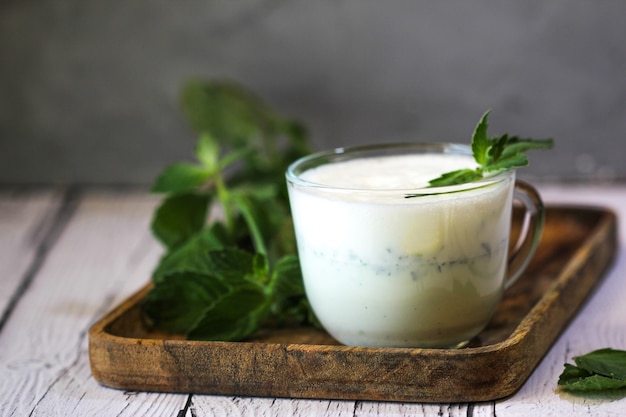 Batido de leite com sorvete e hortelã verde sobre fundo de madeira. Bebida de milkshake.