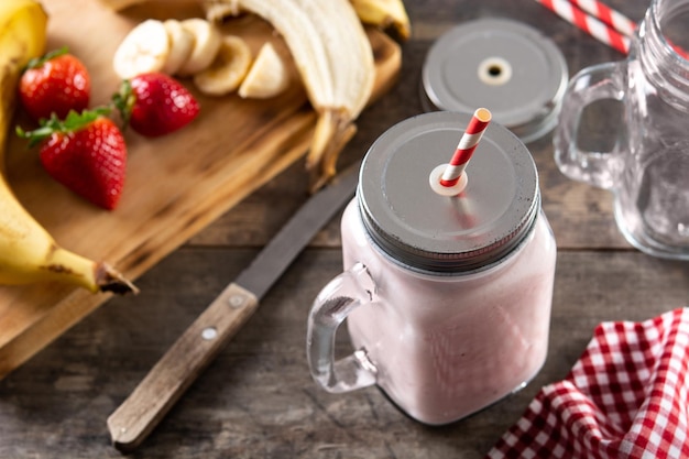 Batido de morango e banana fresco em pote na mesa de madeira