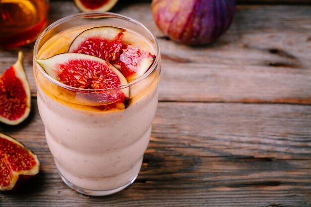 Batido de desayuno saludable con higos frescos y miel en vasos sobre un fondo de madera