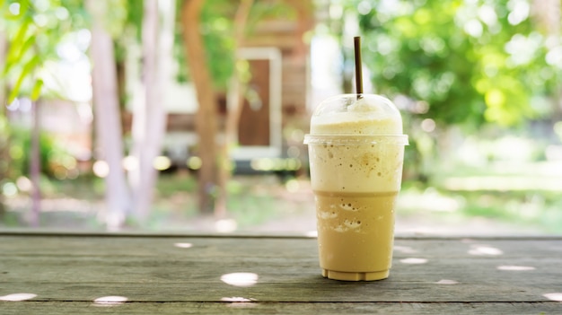 Batido do café em um fundo de madeira da tabela e da planta.