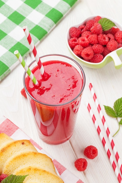 Batido de frambuesa, tarta y bayas en mesa de madera