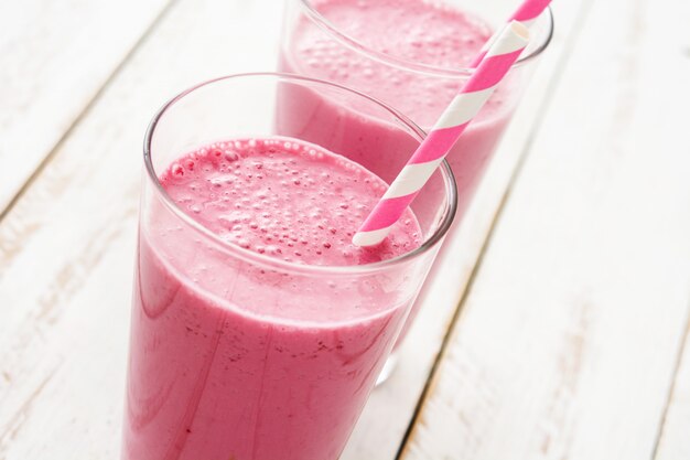 Batido de frambuesa en vidrio sobre mesa de madera blanca