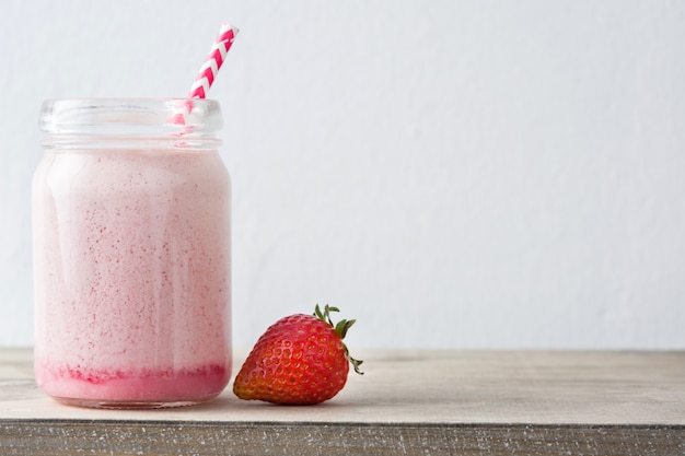 Batido de fresa en frasco en mesa de madera