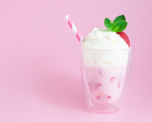 Batido de fresa o batido de leche con crema batida sobre fondo rosa