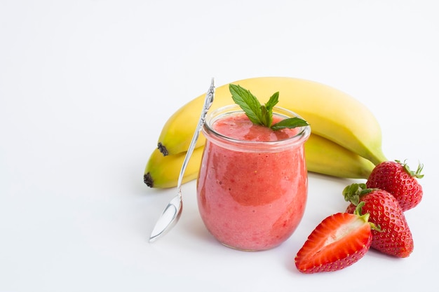 Batido con fresa y plátano en el frasco de vidrio sobre el fondo blanco Espacio de copia Primer plano