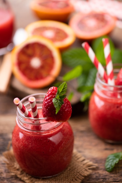 Batido de fresa en tarro de cristal, sobre mesa de madera vieja. de cerca