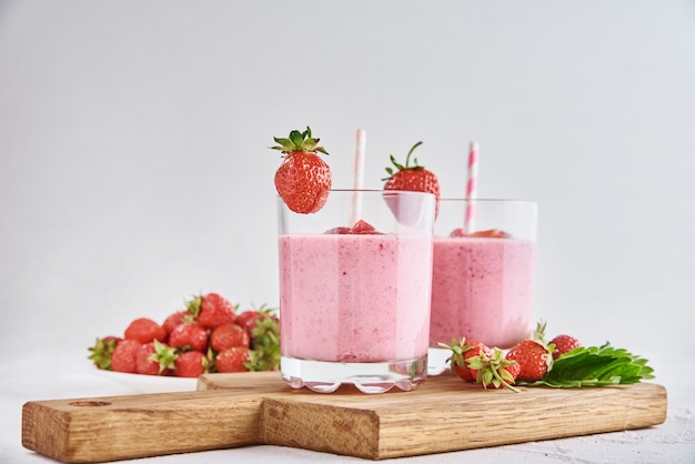 Batido de fresa en vaso con paja y bayas frescas