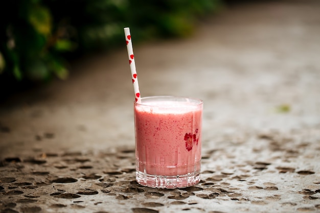 Batido de fresa en un vaso con una pajita en la piedra