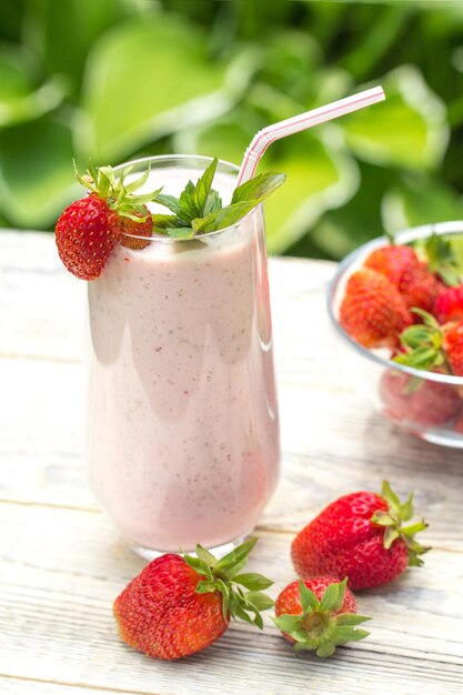 Un batido de fresas frescas se alza sobre un fondo de madera clara