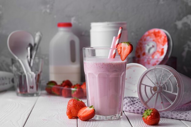 Batido fresco con fresas en una mesa de luz.