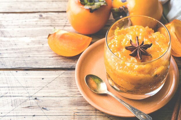 Batido de frutas de caqui con canela y estrellas de anís, espacio de copia de mesa de madera