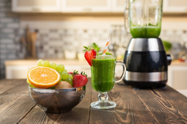 Batido de frutas y verduras frescas en la mesa de la cocina en vidrio