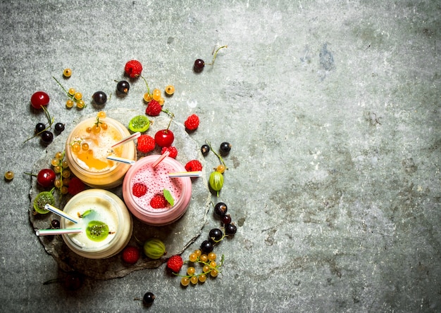 Batido de frutos rojos elaborado con frambuesas, grosellas y grosellas. Sobre un fondo de piedra.