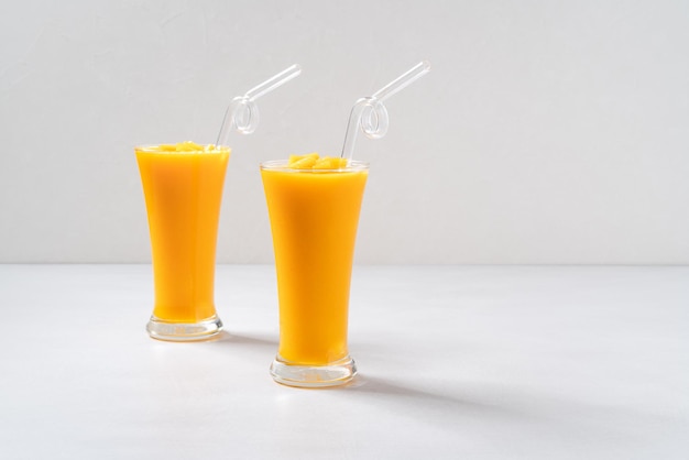 Batido de jugo de mango fresco hermoso y delicioso en vaso de vidrio sobre fondo de mesa gris