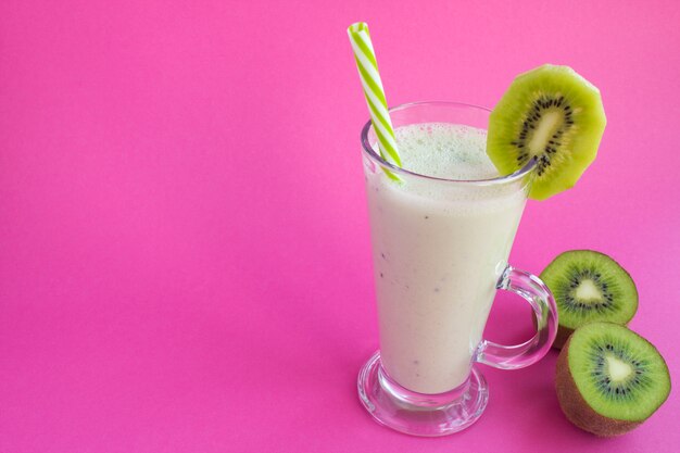 Batido de leche con kiwi en la superficie de color rosa. Copia espacio De cerca.