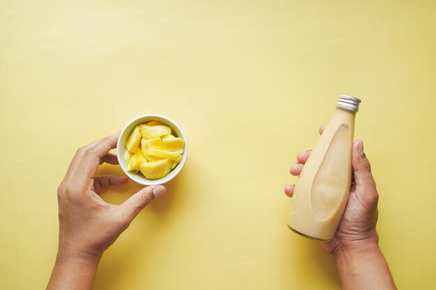 Batido de mango y mango fresco sobre fondo amarillo